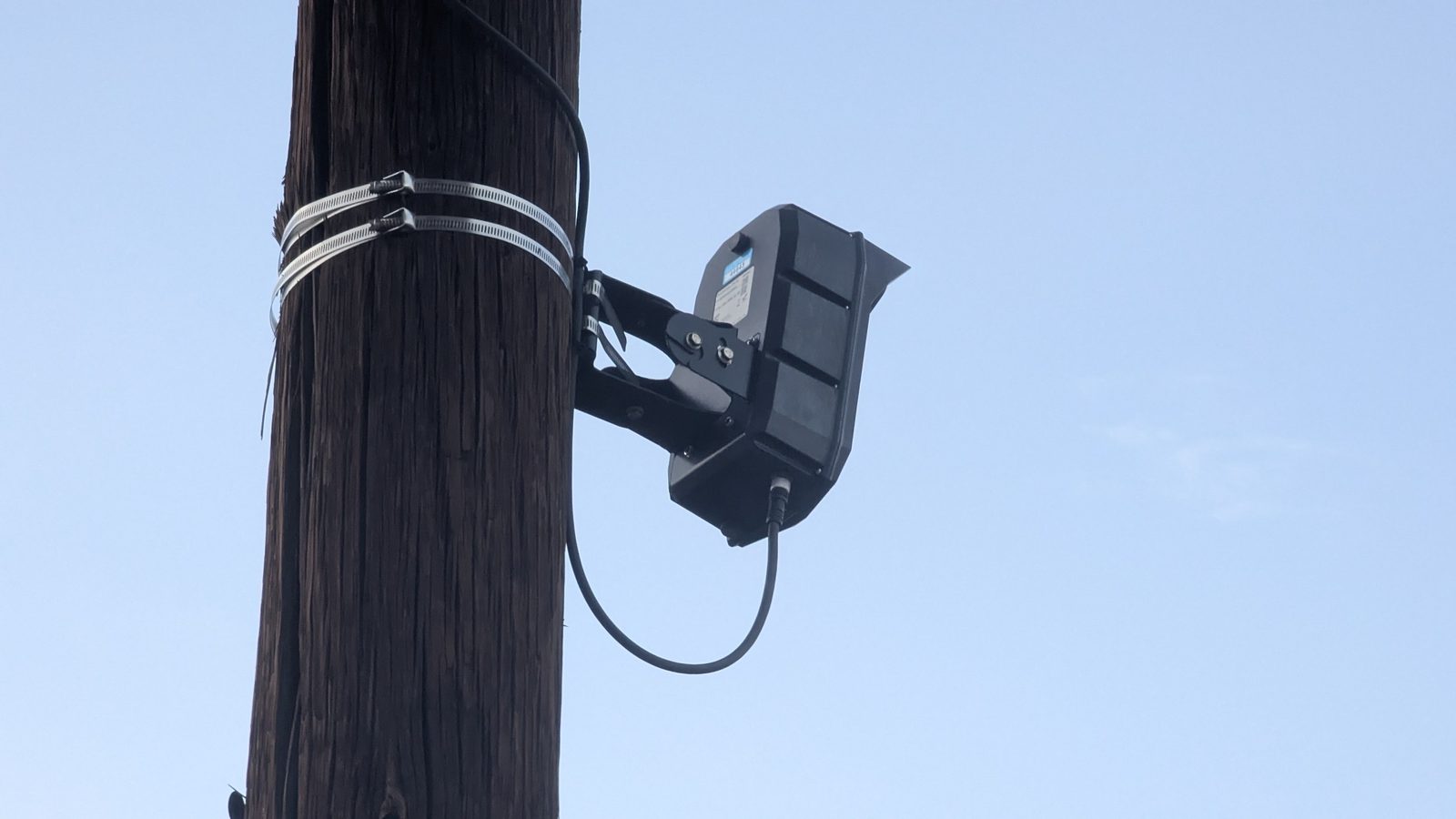 A close view of the roadside camera hardware mounted to a utility pole.
