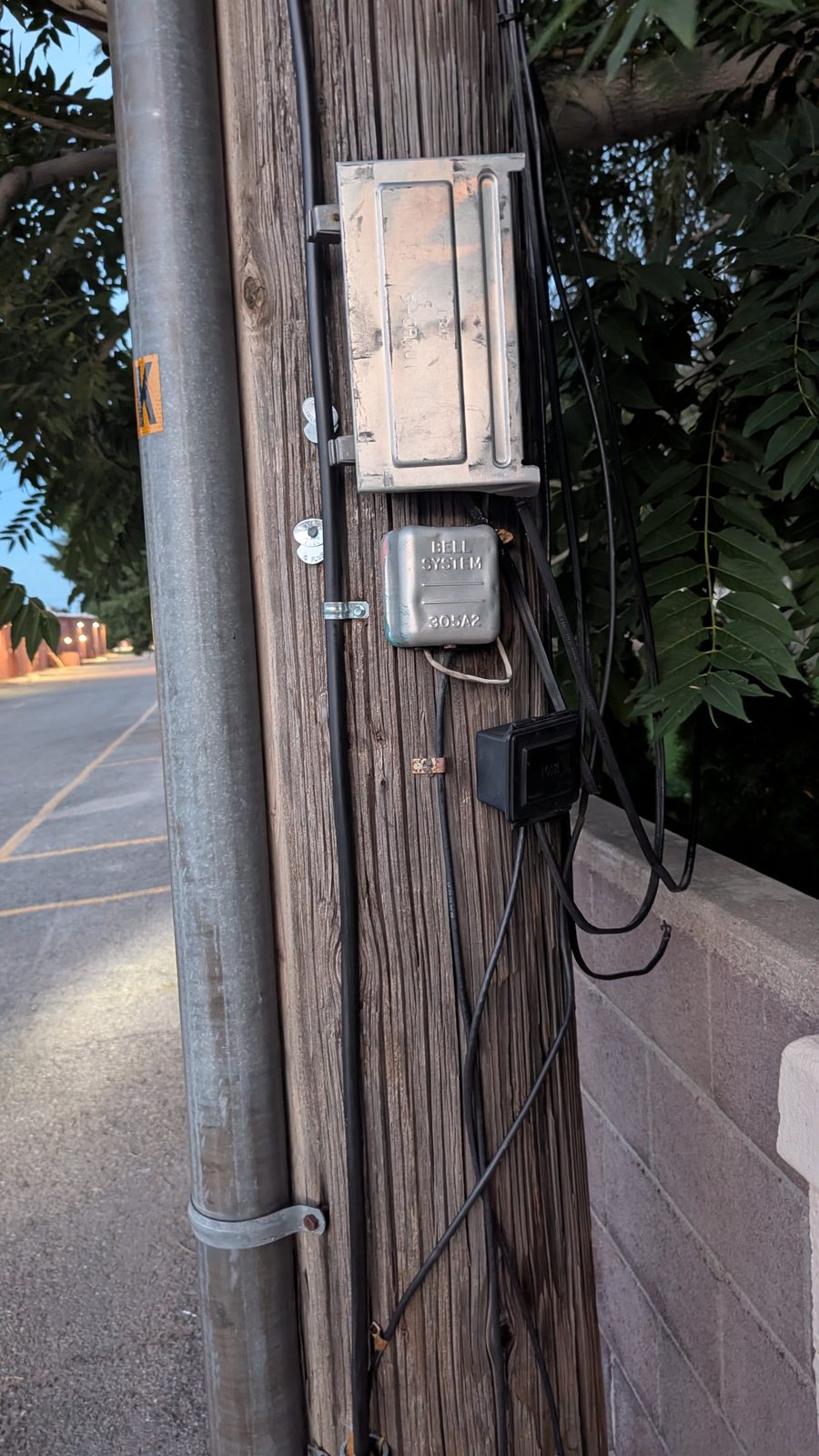 Cables, enclosures, conduit, and tags turn a wooden pole into a vertical equipment rack.