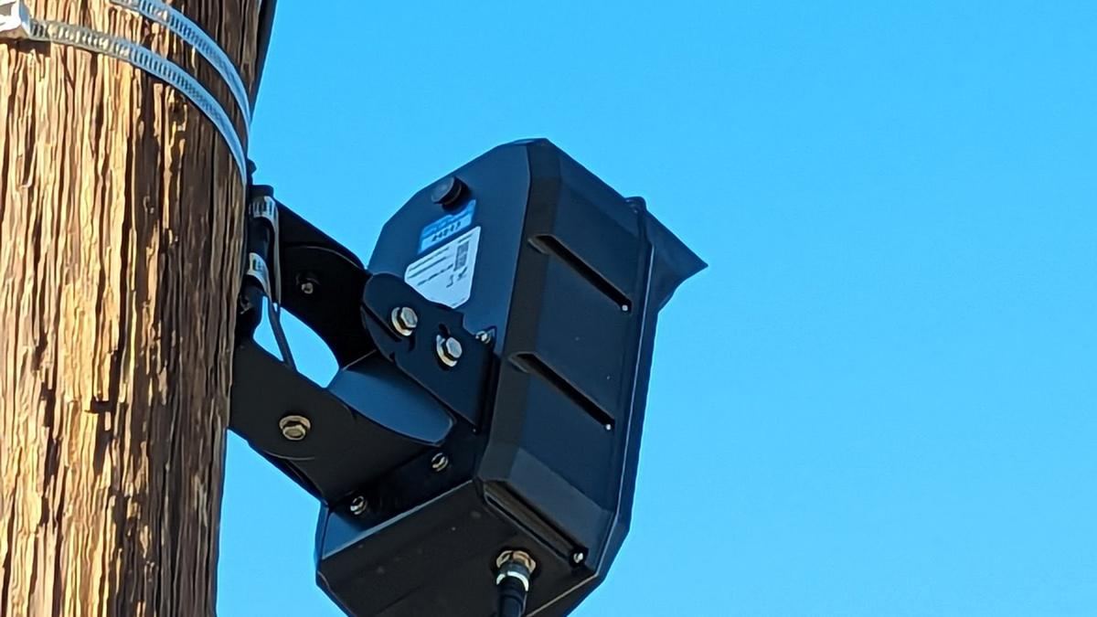 Close-up of a black plate-reader camera on a wooden pole